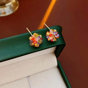 Macro detail of colorful floral stud earrings with rhinestones on a green jewelry box