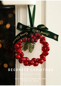 Close-up of red metal bell wreath with green Merry Christmas velvet bow and berries