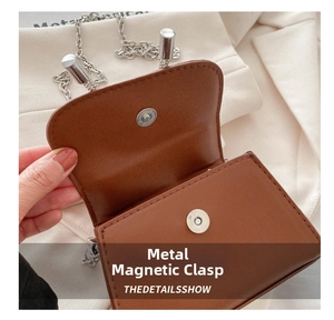 Detail view of the silver magnetic snap closure on a brown leather mini chain bag