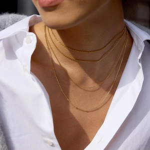 Ensemble de colliers dorés superposés avec mailles gourmette portés sur un mannequin