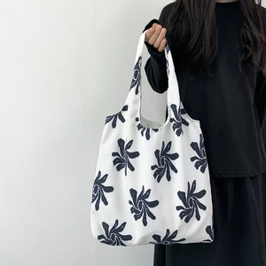 Detail of minimalist white canvas tote bag featuring black floral patterns on shoulder