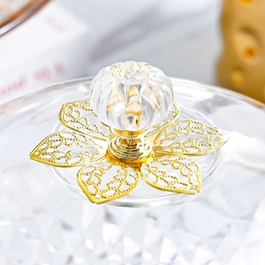 Close-up of a decorative crystal lid handle with golden hollow metal floral base detail