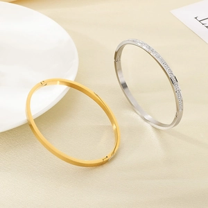 Dettaglio di bracciali ovali placcati oro con cristalli su una superficie strutturata