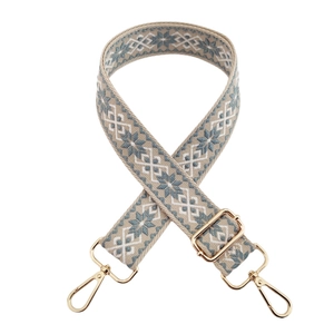 Close-up of geometric star pattern on blue and beige jacquard bag strap with gold metal hooks
