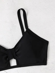 Detail eines schwarzen Bikinioberteils mit schmalen Trägern, Knotendetail und Ausschnitt