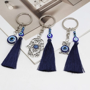 Close-up of evil eye hamsa hand and owl keychains with elegant blue tassels