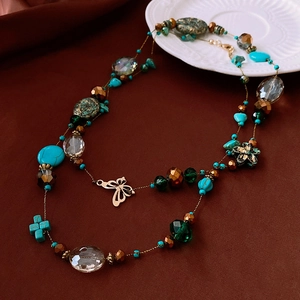 Detail of bohemian layered necklace with turquoise beads, metallic butterfly and flower charms