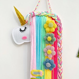 Détail du support à barrettes licorne avec glands colorés et fleurs en feutrine