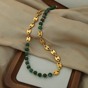 Retro vintage necklace with green agate beads and golden pig-nose links on silk background
