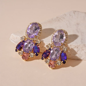 Detail of luxury oval geometric earrings with colorful crystals on stone display