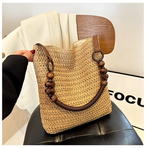 Detail of hand-woven straw tote bag featuring dark brown wooden bead handles and rich texture