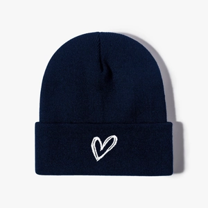 Navy blue winter knitted beanie hat with white embroidered heart detail on white background