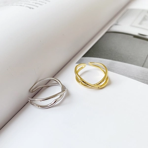 Detail of minimalist gold and silver cross-line open rings on a book background