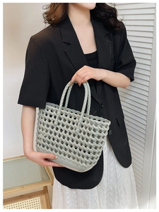 Close-up of a light grey woven jelly basket bag held by a model for a casual summer look