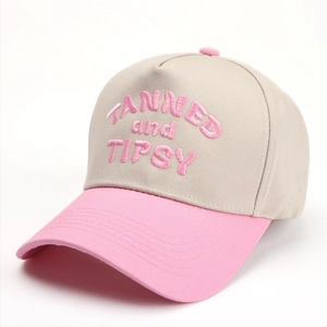 Detail of embroidered Tanned and Tipsy text on a beige and pink cotton baseball cap