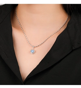 Close-up of a 925 sterling silver heart necklace with a blue gemstone on a model