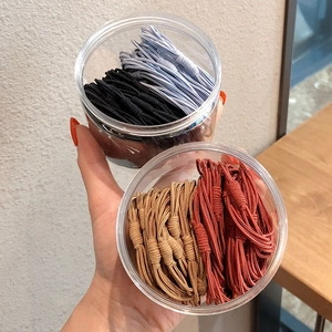Close-up of colorful braided elastic hair bands stored in two clear plastic jars