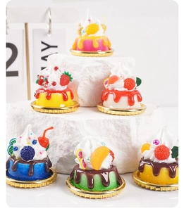 Macro view of miniature artificial fruit cakes on gold trays for dessert shop display