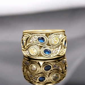 Détail d'une bague dorée vintage avec motifs floraux évidés et pierres précieuses