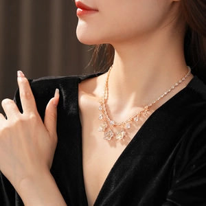 Close-up of golden necklace with floral and teardrop zircon pendants on a model's neck
