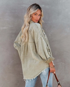 Close-up of distressed ripped details and raw hem on the back of an oversized denim jacket