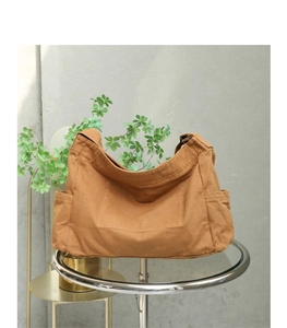 Close-up of caramel canvas messenger bag showing side pockets and adjustable strap buckle
