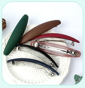 Set of six matte spring hair clips in various vintage colors displayed on a ceramic plate