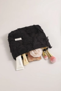 Close-up of black textured makeup bag with tassel fabric showing storage capacity