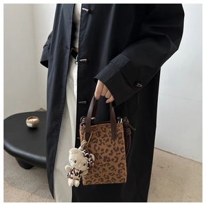 Detailed close-up of leopard print tote bag with plush kitten charm and canvas texture