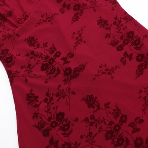 Gros plan sur un tissu rouge foncé avec motifs floraux floqués et texture semi-transparente