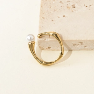 Minimalist gold titanium steel irregular open ring with white pearl on stone background