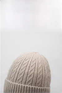 Detailed cable knit texture of a warm beige beanie showing high-quality winter stitching