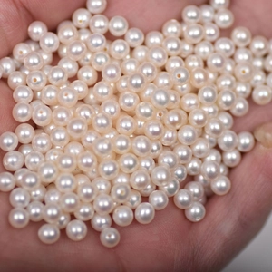 Close-up of 4mm white freshwater pearls held in hand for DIY jewelry making
