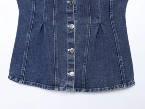 Detail of washed denim corset top featuring metallic buttons and slimming waist pleats