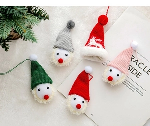 Detail von farbenfrohen gestrickten Weihnachtsanhängern auf weißem Plüschhintergrund