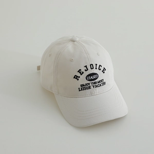 Detail of embroidered letters on cream cotton twill baseball cap with curved brim