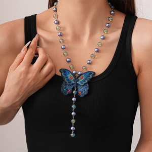 Detailed view of an embroidered butterfly pendant on a beaded long necklace worn by a model