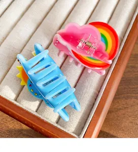 Close-up of sky-themed acrylic hair claws with rainbow and sun rhinestone patterns