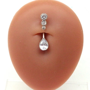 Detailed view of a silver navel ring with vertical round gems and a pear-shaped drop