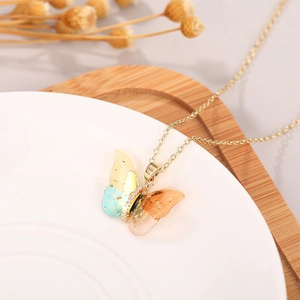 Detail of butterfly necklace with resin wings, gold flakes and sparkling rhinestones