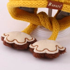 Close-up of knit earflap hat detail with leather label and cute plush bear paw charms