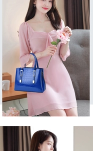 Détail d'un sac à main bleu avec texture crocodile et fermoir argenté porté par un mannequin