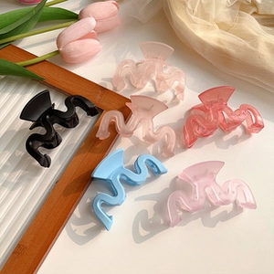 Detail of matte wavy hair clips in assorted colors like sky blue, pink, and black
