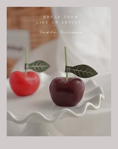 Detalle macro de velas con forma de cereza roja y morada con tallos verdes decorativos