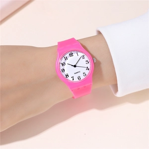 Close-up of pink quartz watch on wrist showing white dial and soft silicone strap