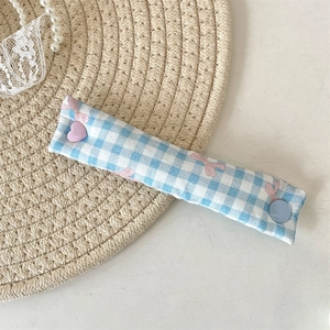 Close-up of blue checkered fabric cable organizer with pink bow and colorful buttons
