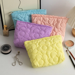 Dettaglio di borse per cosmetici trapuntate a fiori in blu, rosa, viola e giallo