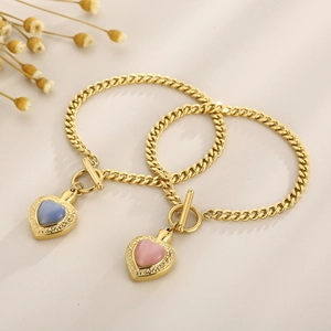 Détail de bracelets dorés avec pierres en cœur bleues et roses et fermoirs en T