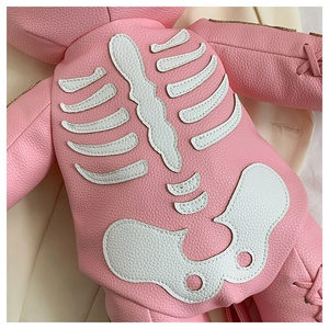 Detailed close-up of pink litchi grain leather with white skull applique and stitching