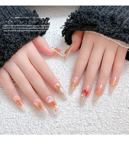 Detailed view of brown Maillard style resin camellia and bow nail charms on manicured nails